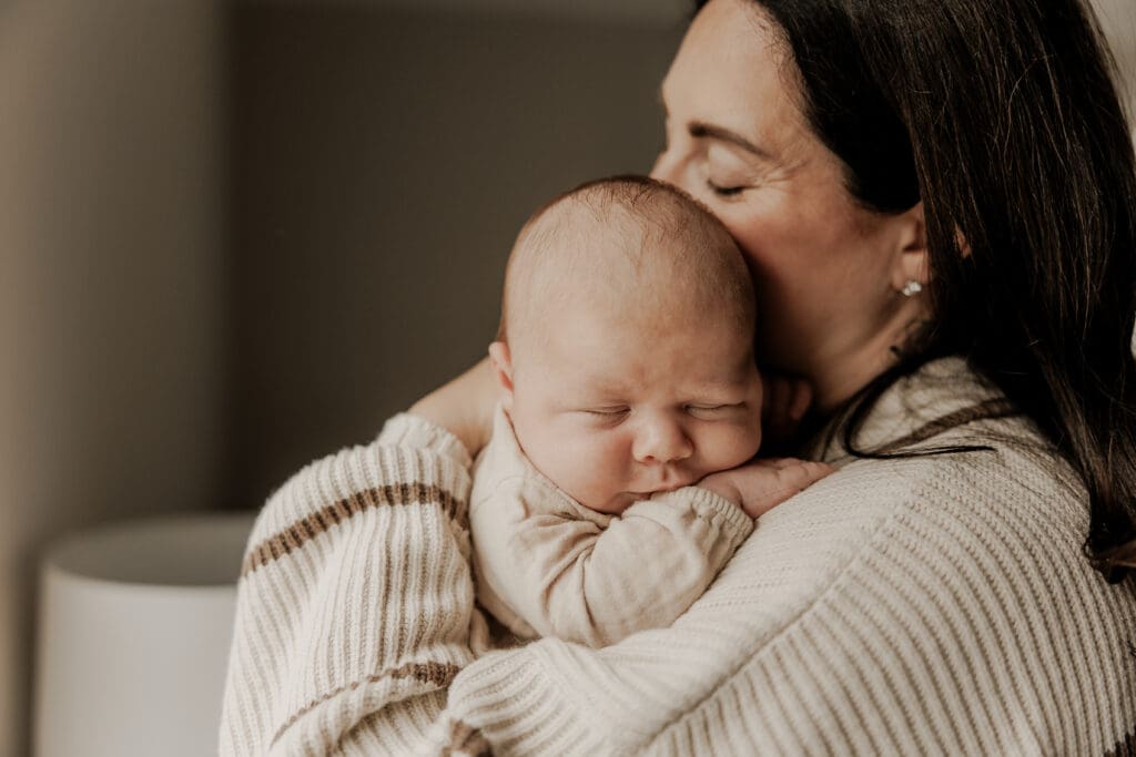 Close-up of a sleeping newborn nestled against mother's chest in a soft knit sweater — cozy, heartfelt newborn photography in Basking Ridge, New Jersey.
